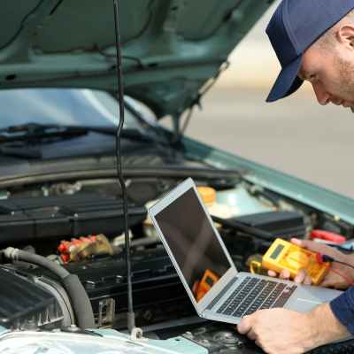 A technician performing diagnostic services on a vehicle with a laptop.